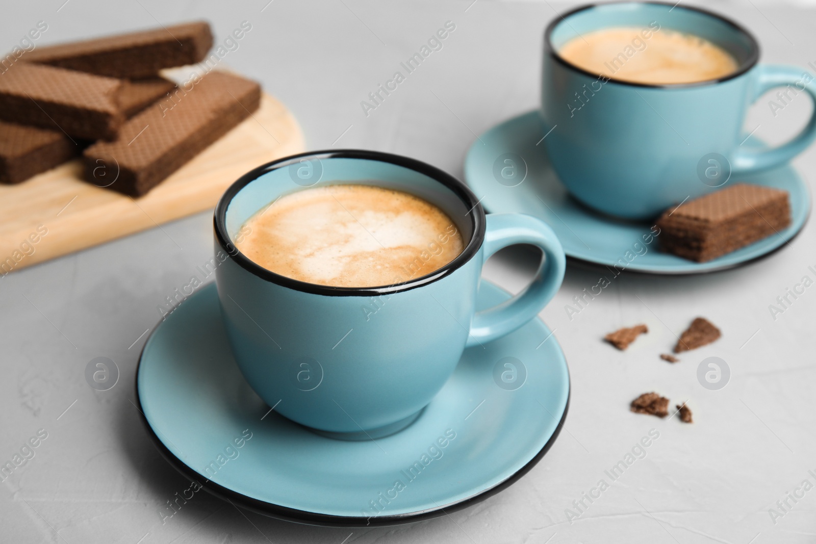 Photo of Delicious coffee and wafers for breakfast on grey table