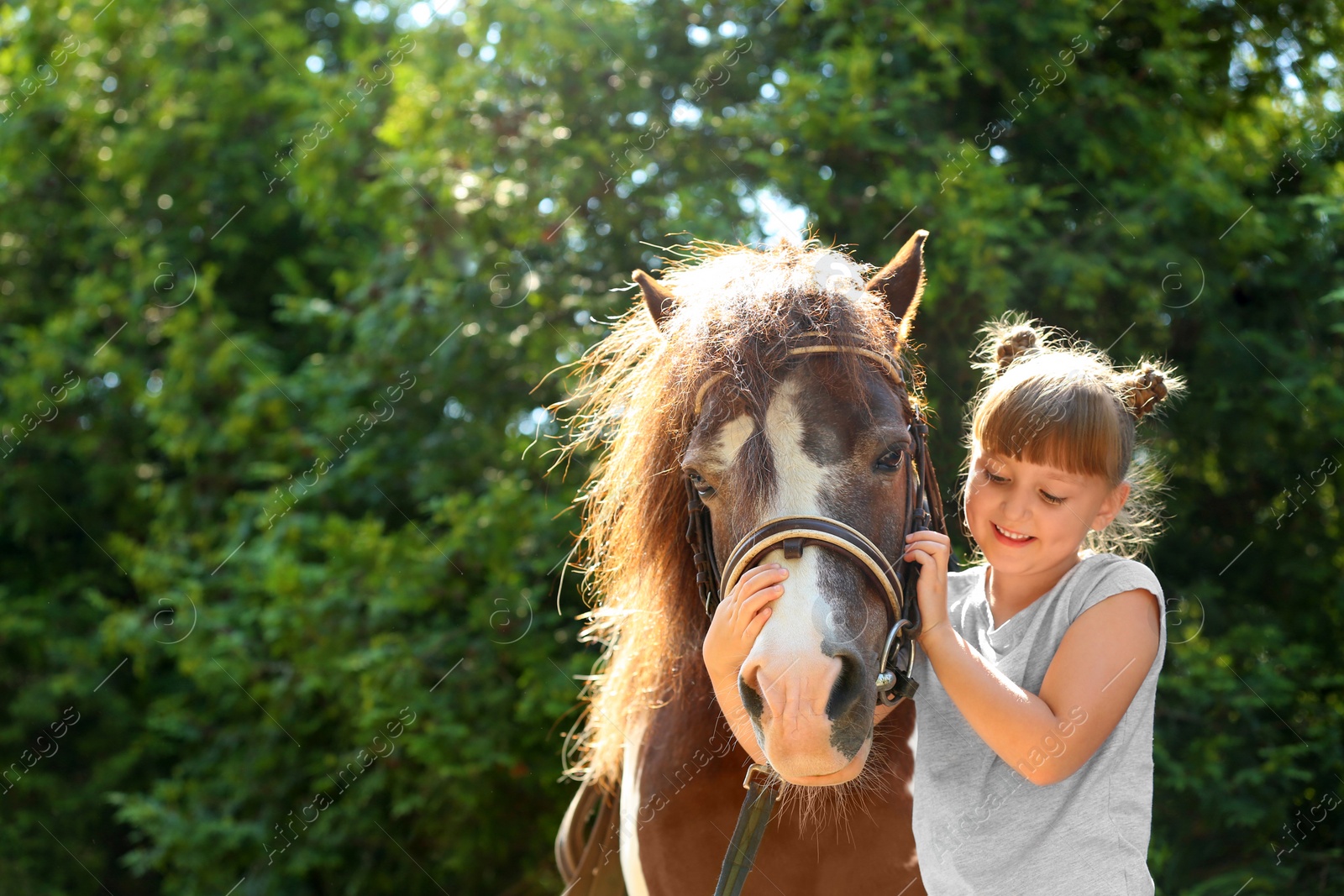 Photo of Cute little girl with her pony in green park