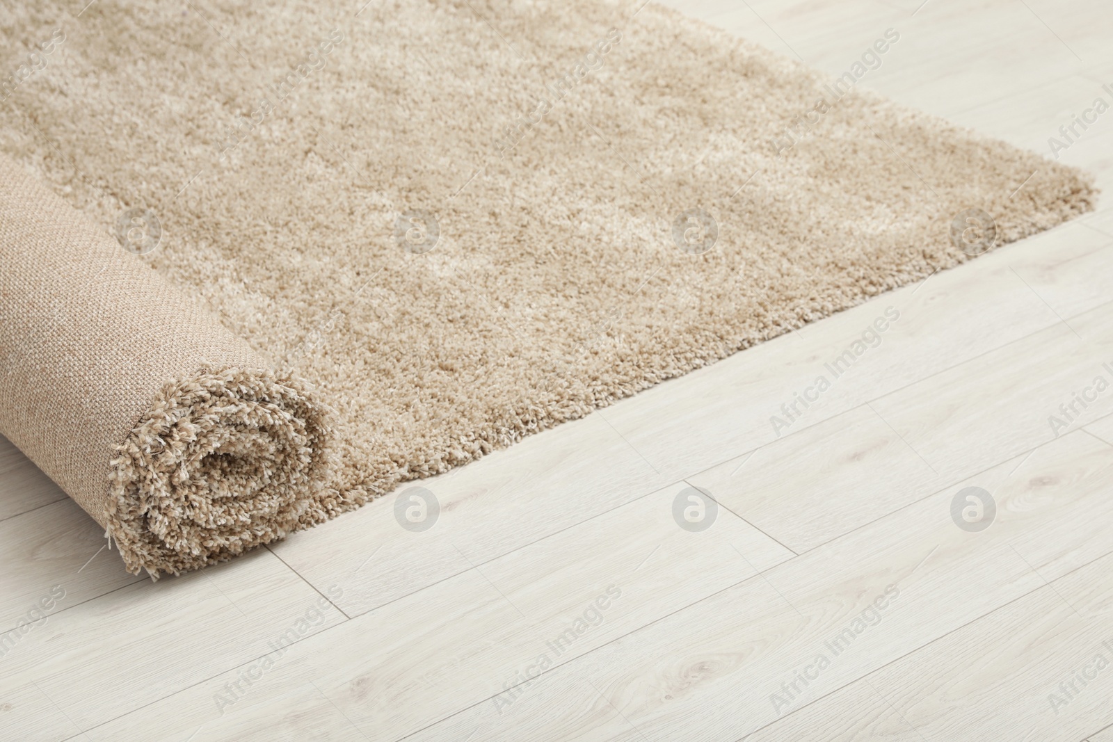 Photo of Rolled beige carpet on floor, closeup. Space for text