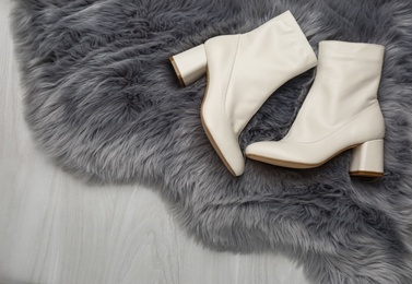Photo of Pair of stylish leather shoes on faux fur, flat lay
