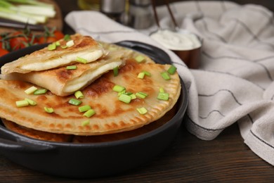 Photo of Delicious fried chebureki with cheese and green onion on wooden table, space for text