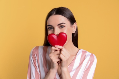 Portrait of young woman with decorative heart on color background