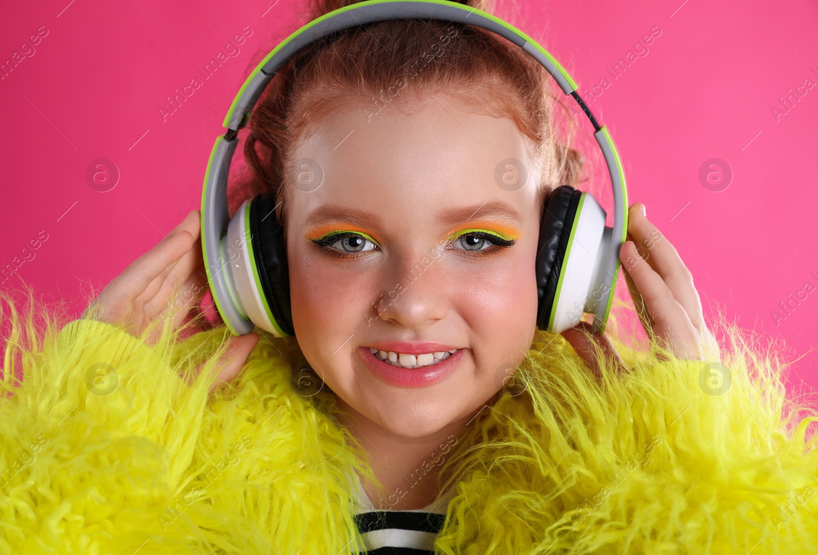 Photo of Cute indie girl with headphones on pink background