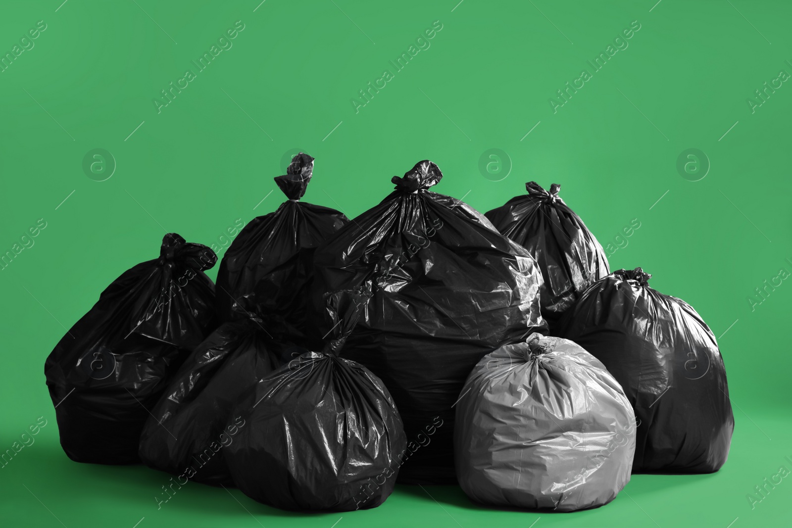 Photo of Trash bags full of garbage on green background