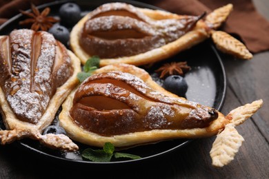 Photo of Delicious pears baked in puff pastry with powdered sugar served on wooden table, closeup