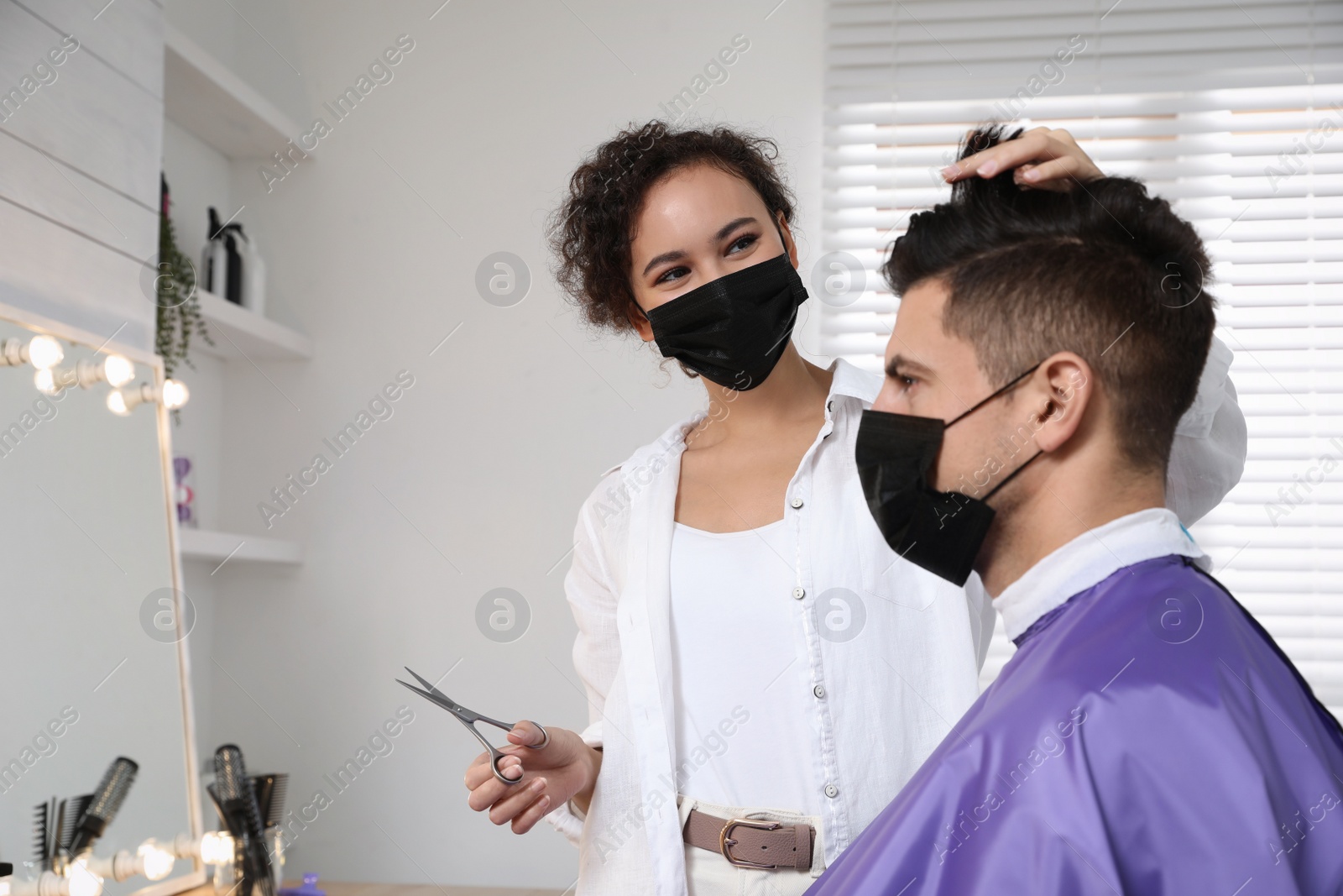 Photo of Professional stylist working with client in salon. Hairdressing services during Coronavirus quarantine