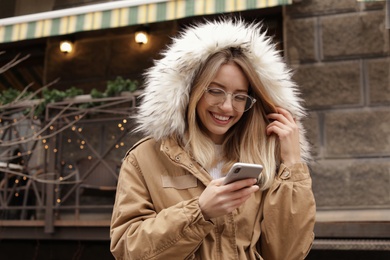 Photo of Beautiful young woman using mobile phone outdoors