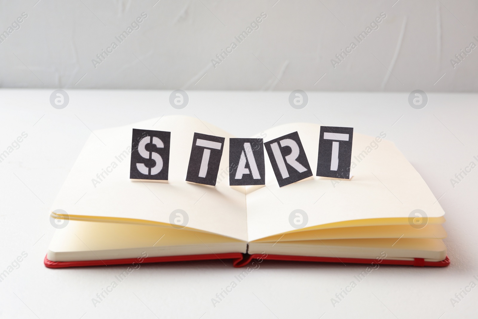 Photo of Sheets of paper with word Start and notebook on white table