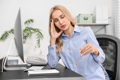 Overwhelmed woman with glasses at table in office