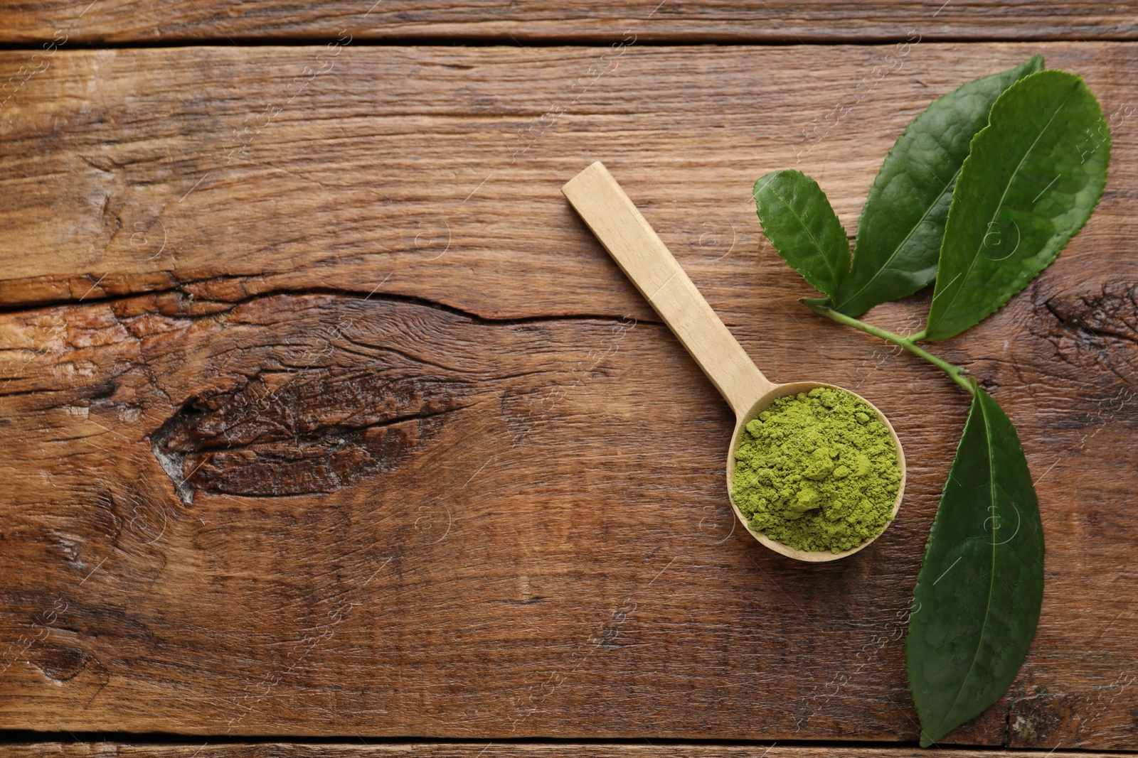 Photo of Scoop with green matcha powder on wooden table, flat lay. Space for text