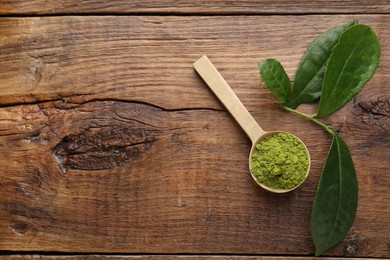 Photo of Scoop with green matcha powder on wooden table, flat lay. Space for text