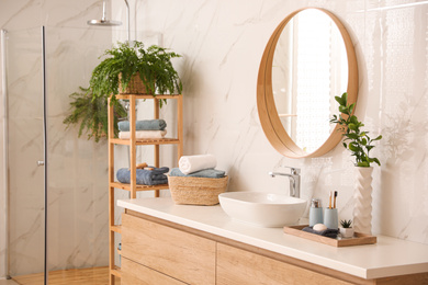 Stylish bathroom interior with countertop, shower stall and houseplants. Design idea