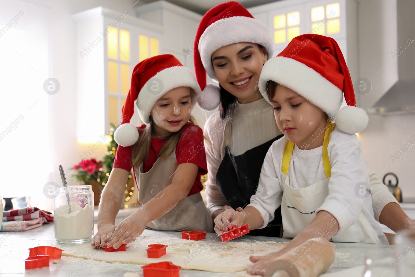 Photo of Mother and her cute little children making Christmas cookies in kitchen