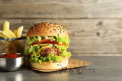 Photo of Burger with delicious patty, french fries and sauce on gray table, space for text