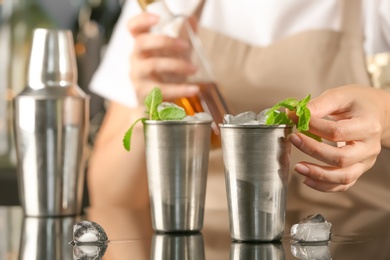 Bartender preparing delicious mint julep cocktail at table