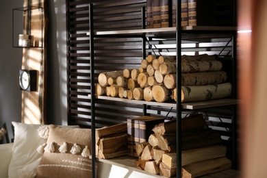 Shelving unit with stacked firewood and books near wall in room. Idea for interior design