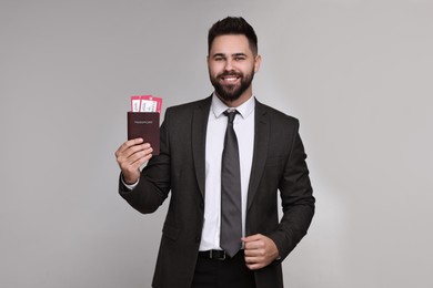 Photo of Happy businessman with passport and tickets on grey background