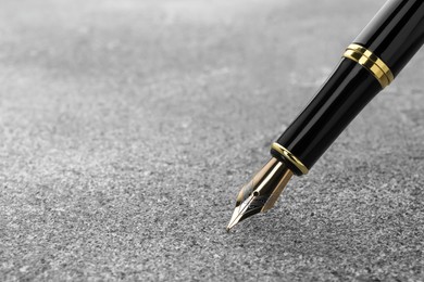 Stylish fountain pen on grey textured table, closeup. Space for text