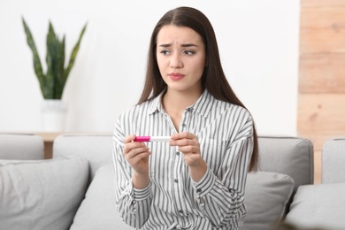 Photo of Young woman with pregnancy test at home. Gynecology and childbirth