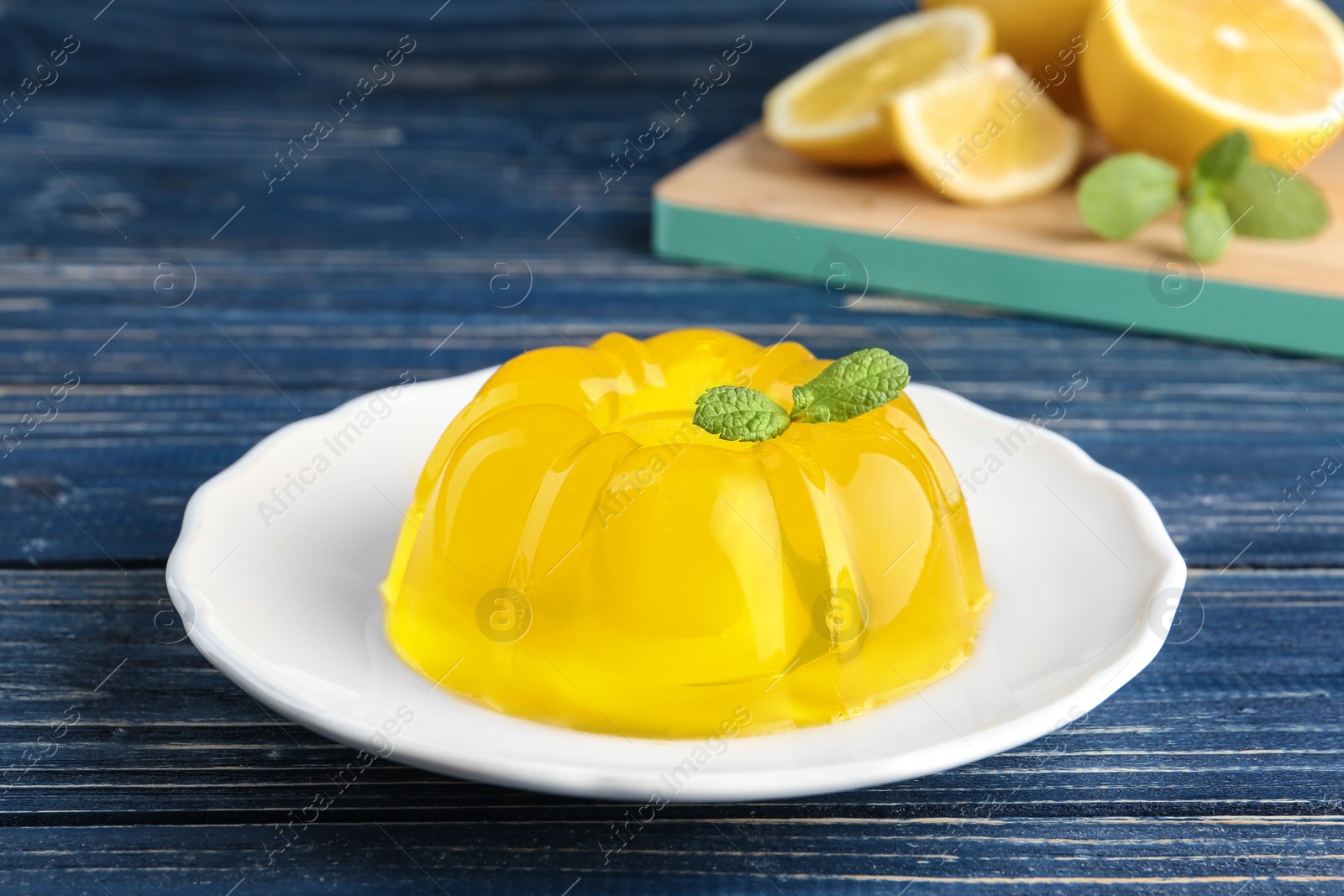 Photo of Plate with lemon jelly and mint on blue wooden table
