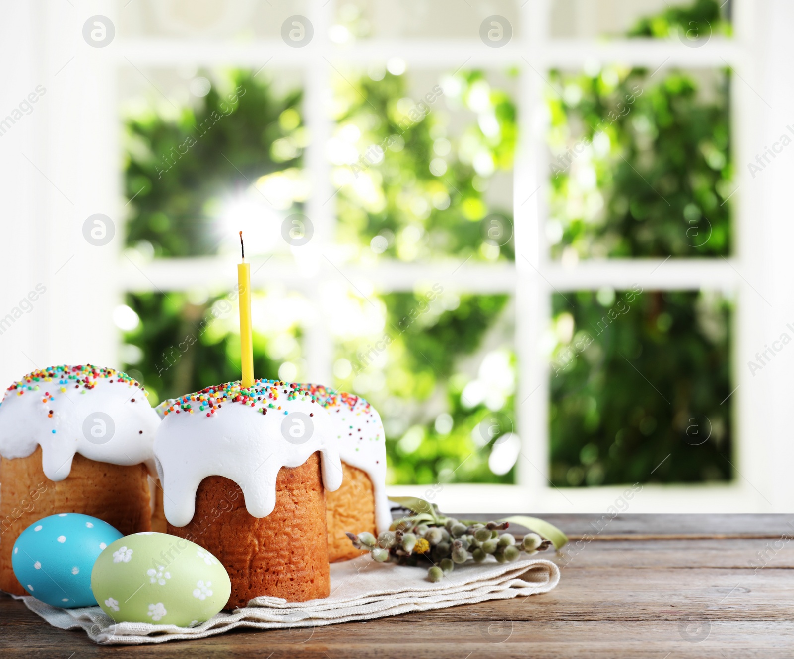 Image of Delicious Easter cakes and painted eggs on wooden table indoors. Space for text