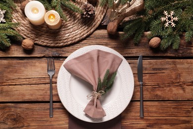 Festive place setting with beautiful dishware, cutlery and fabric napkin for Christmas dinner on wooden table, flat lay