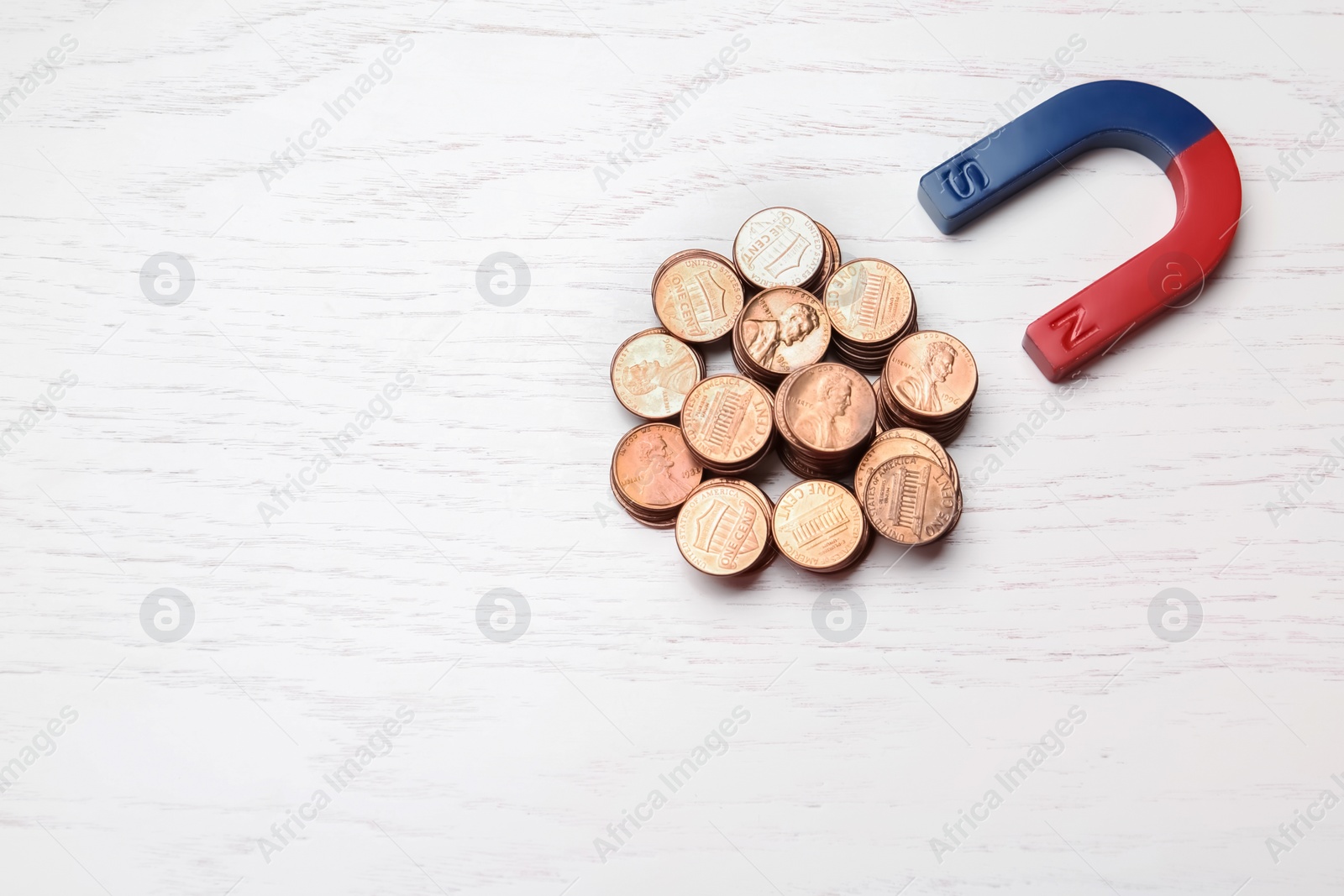 Photo of Magnet attracting coins on wooden background, top view with space for text. Business concept
