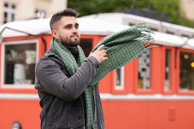 Photo of Smiling man in warm scarf outdoors. Space for text