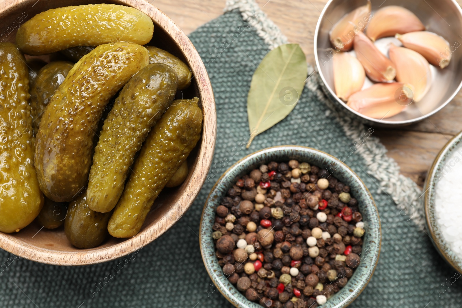 Photo of Tasty pickled cucumbers in bowl and spices on table, flat lay