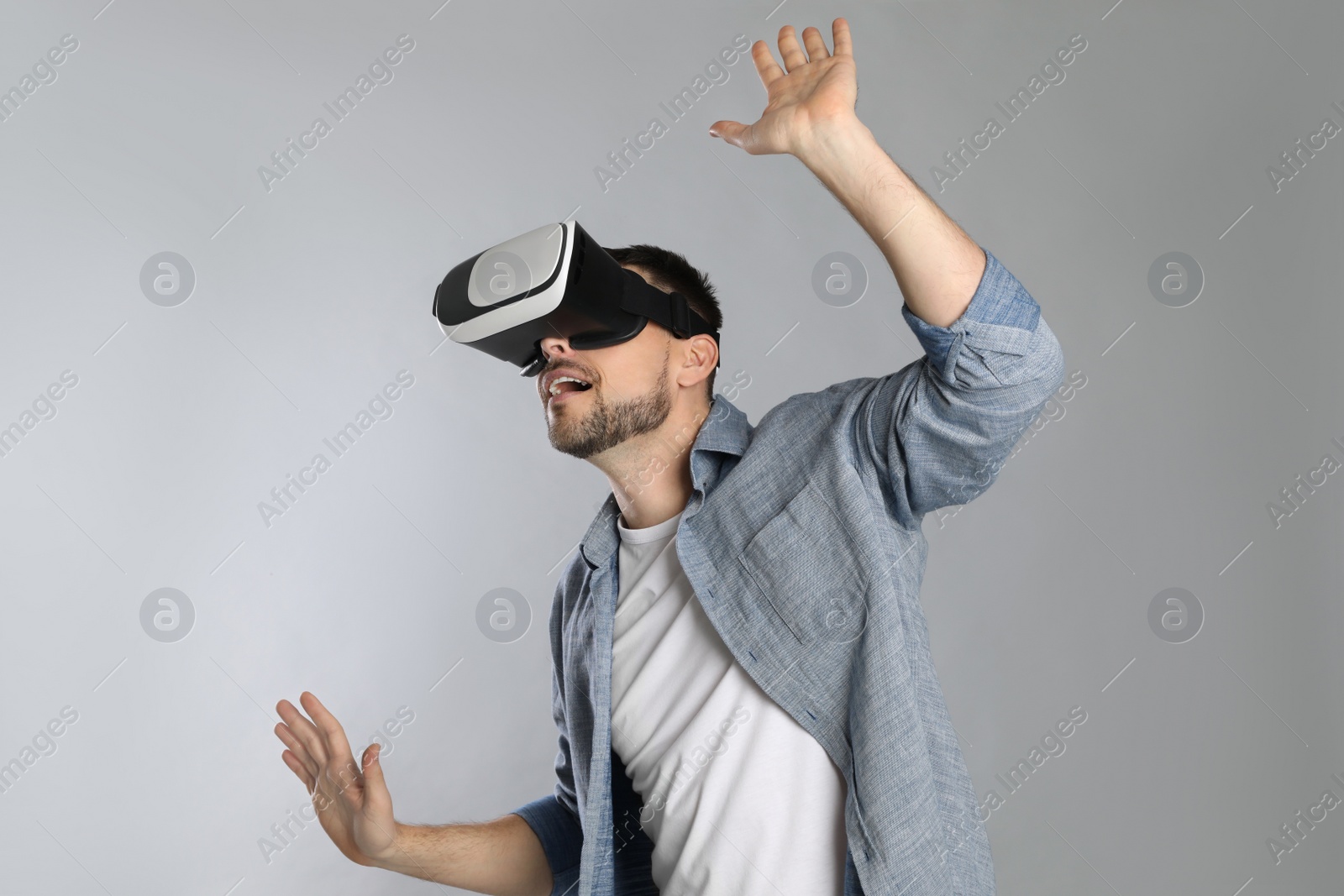 Photo of Man using virtual reality headset on grey background