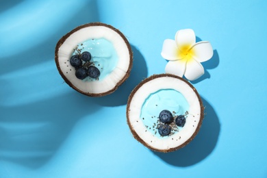 Coconuts with yummy spirulina smoothie on color background, top view