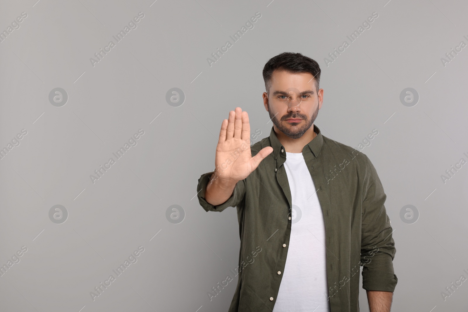 Photo of Handsome man showing stop gesture on light grey background, space for text