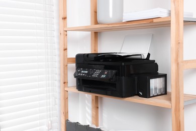 Photo of Modern printer with paper on wooden shelf indoors