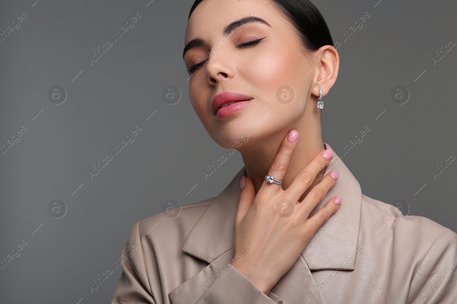 Photo of Beautiful young woman with elegant jewelry on dark grey background