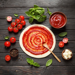 Photo of Flat lay composition with pizza crust and ingredients on dark wooden table