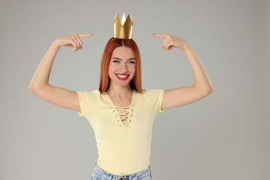Beautiful young woman with princess crown on light grey background