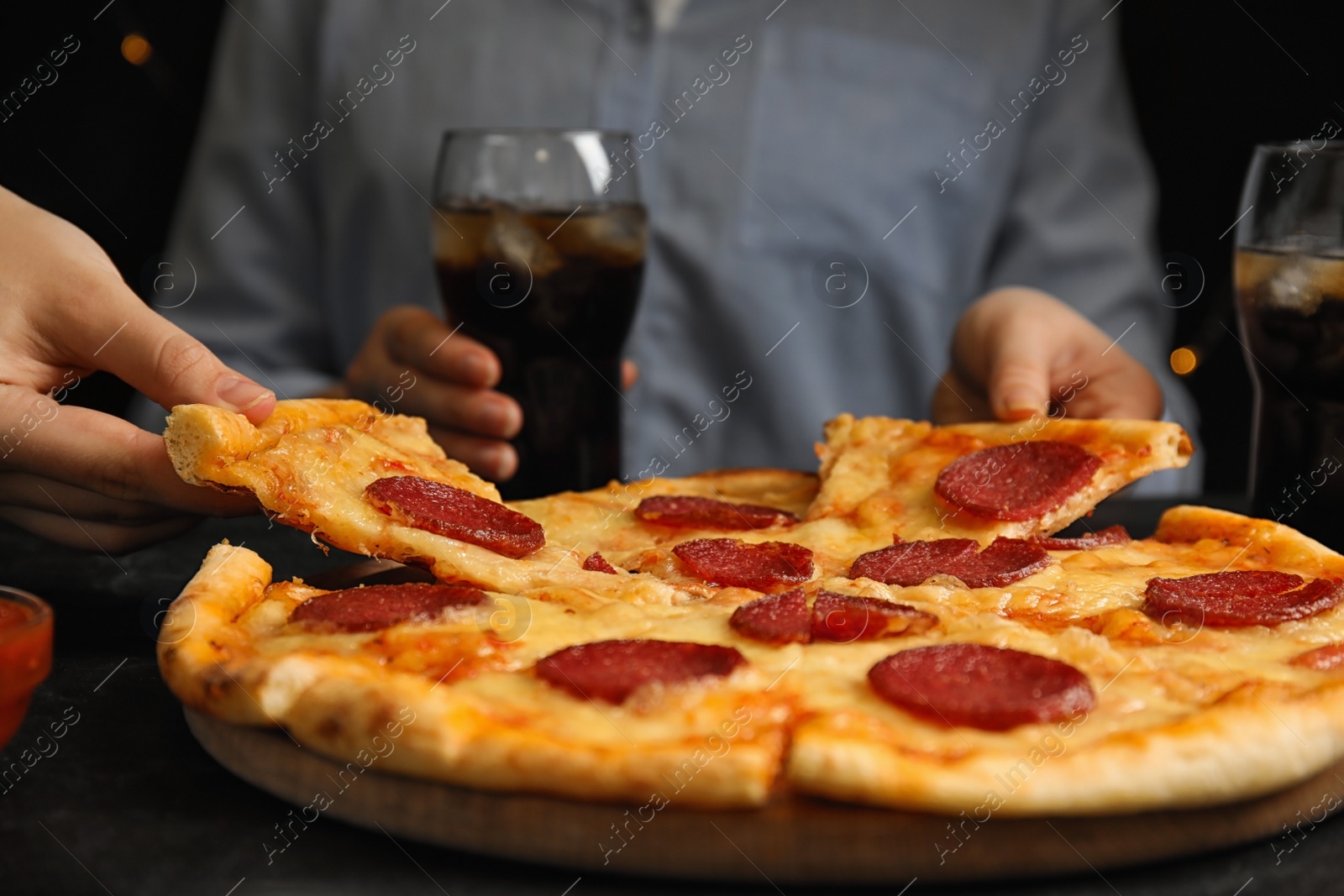 Photo of Women taking tasty pepperoni pizza at table, closeup