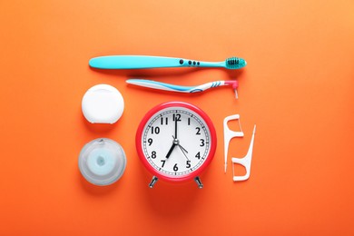 Photo of Flat lay composition with dental flosses, alarm clock and different teeth care products on orange background