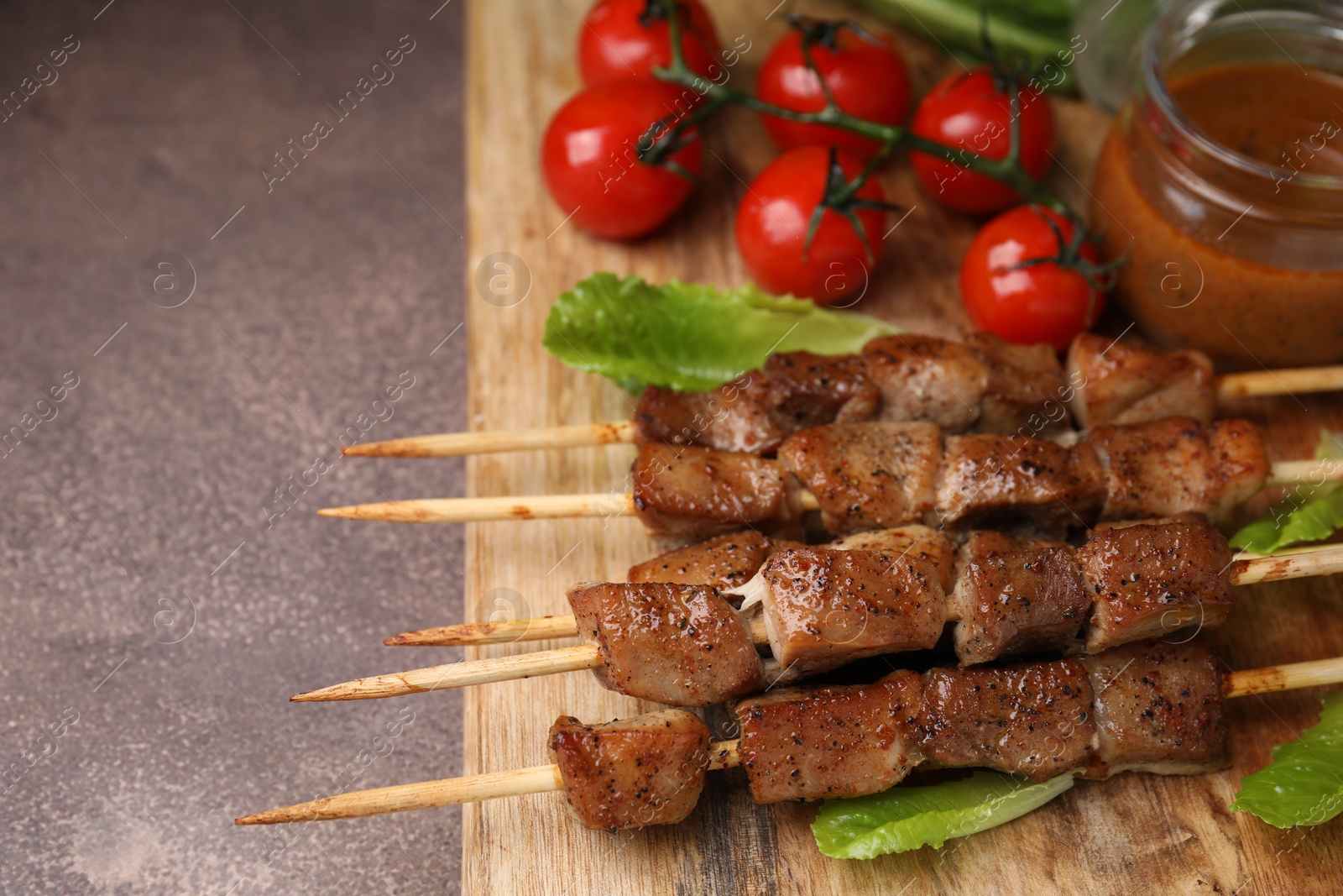 Photo of Tasty cooked marinated meat served with sauce and tomatoes on grey table, flat lay. Space for text