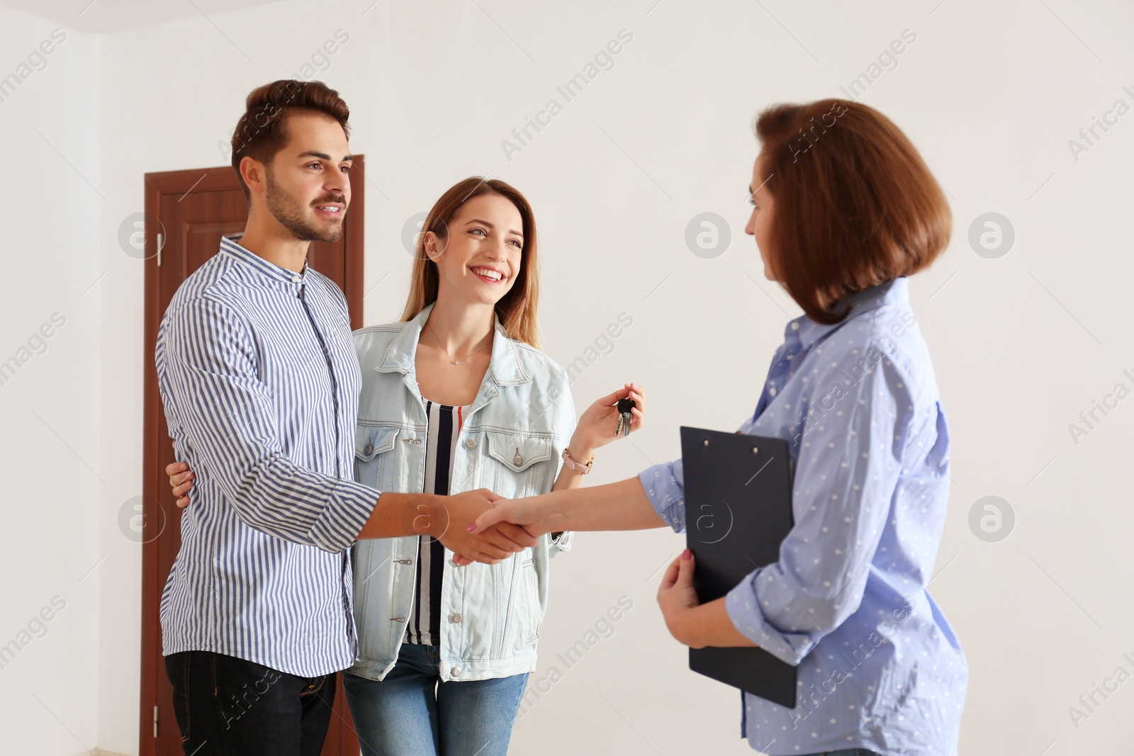 Photo of Real estate agent with young couple in new apartment