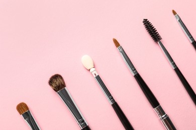Different makeup brushes on pink background, flat lay. Space for text
