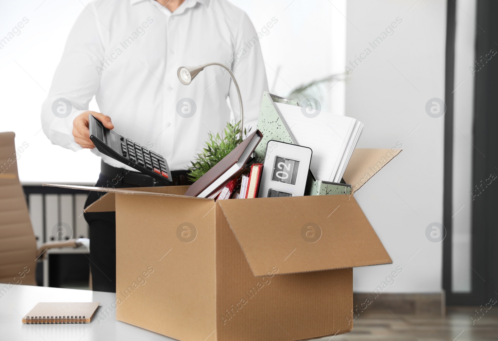 Photo of Young man packing stuff in box at office, closeup