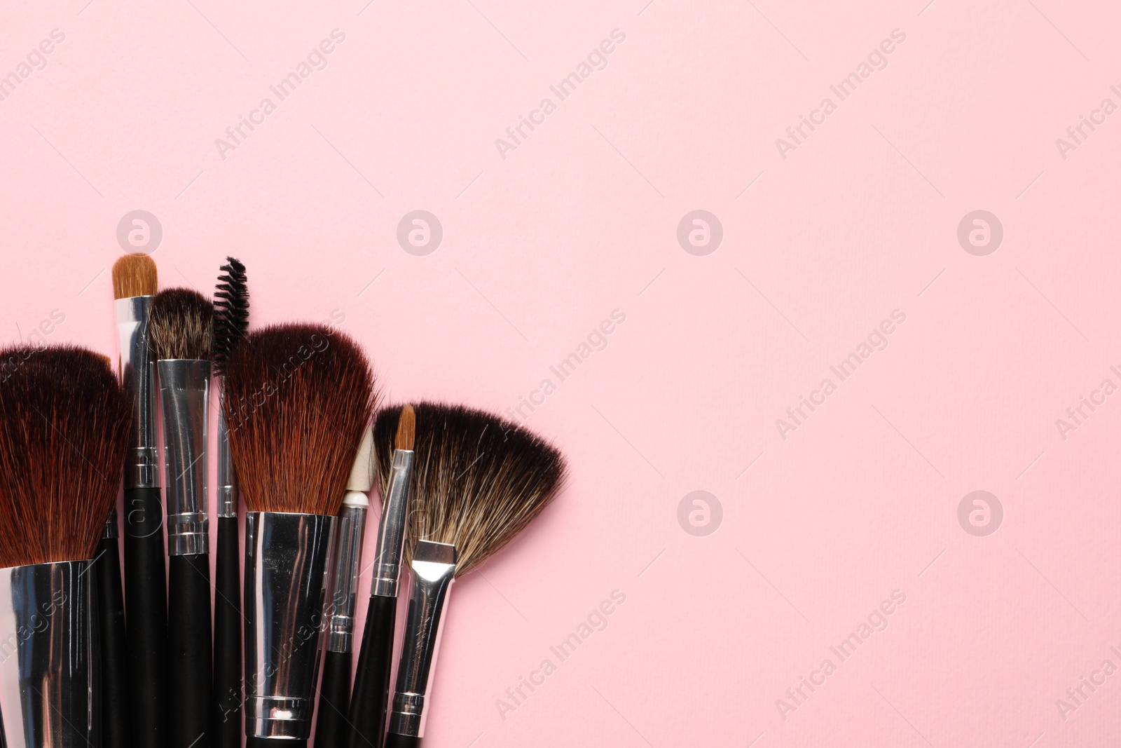 Photo of Different makeup brushes on pink background, flat lay. Space for text