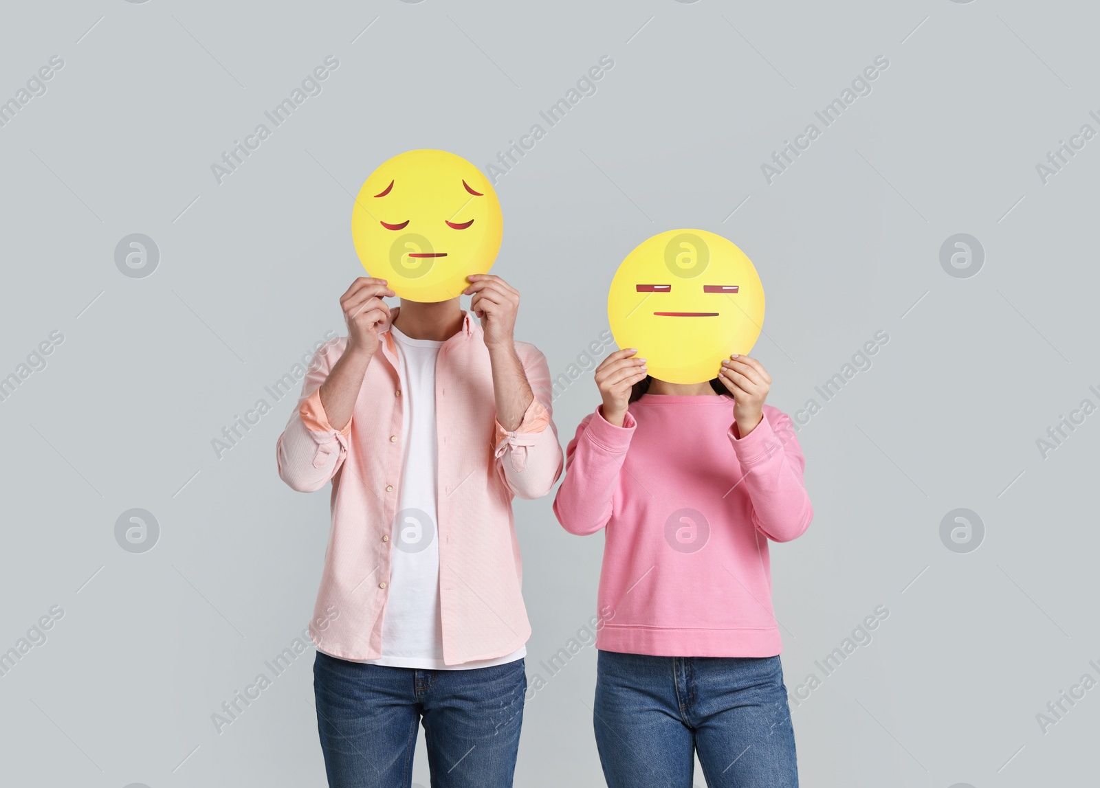 Photo of People covering faces with sad emoticons on grey background