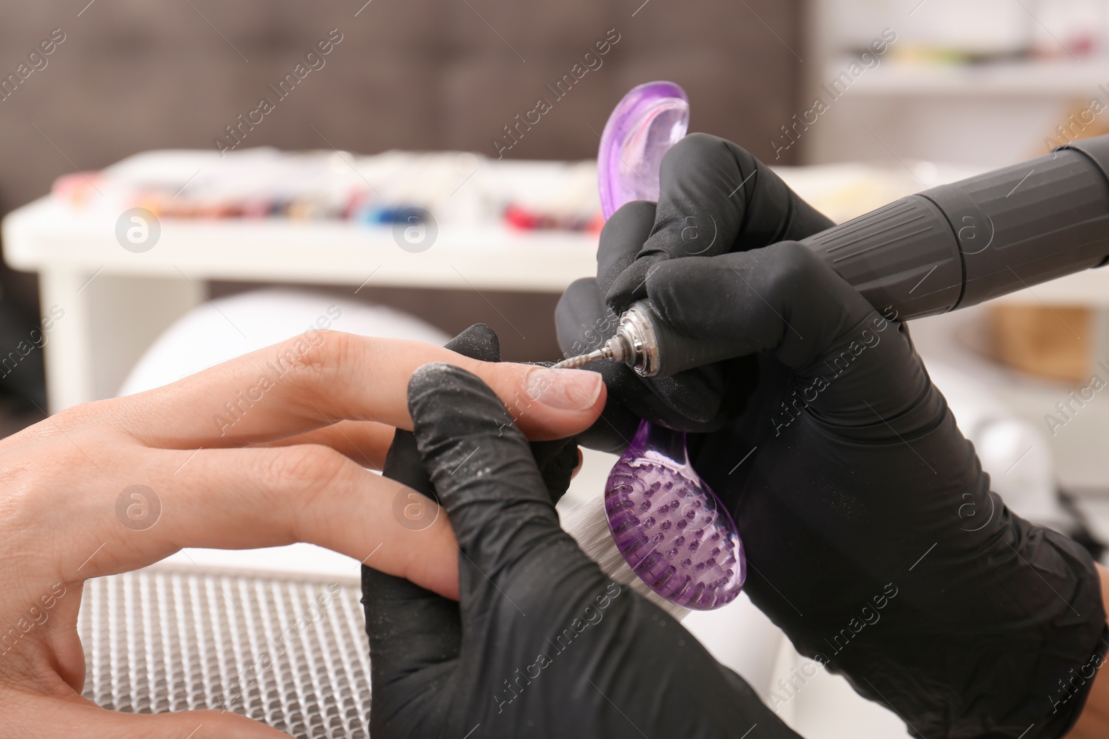 Photo of Professional manicurist working with client in salon, closeup