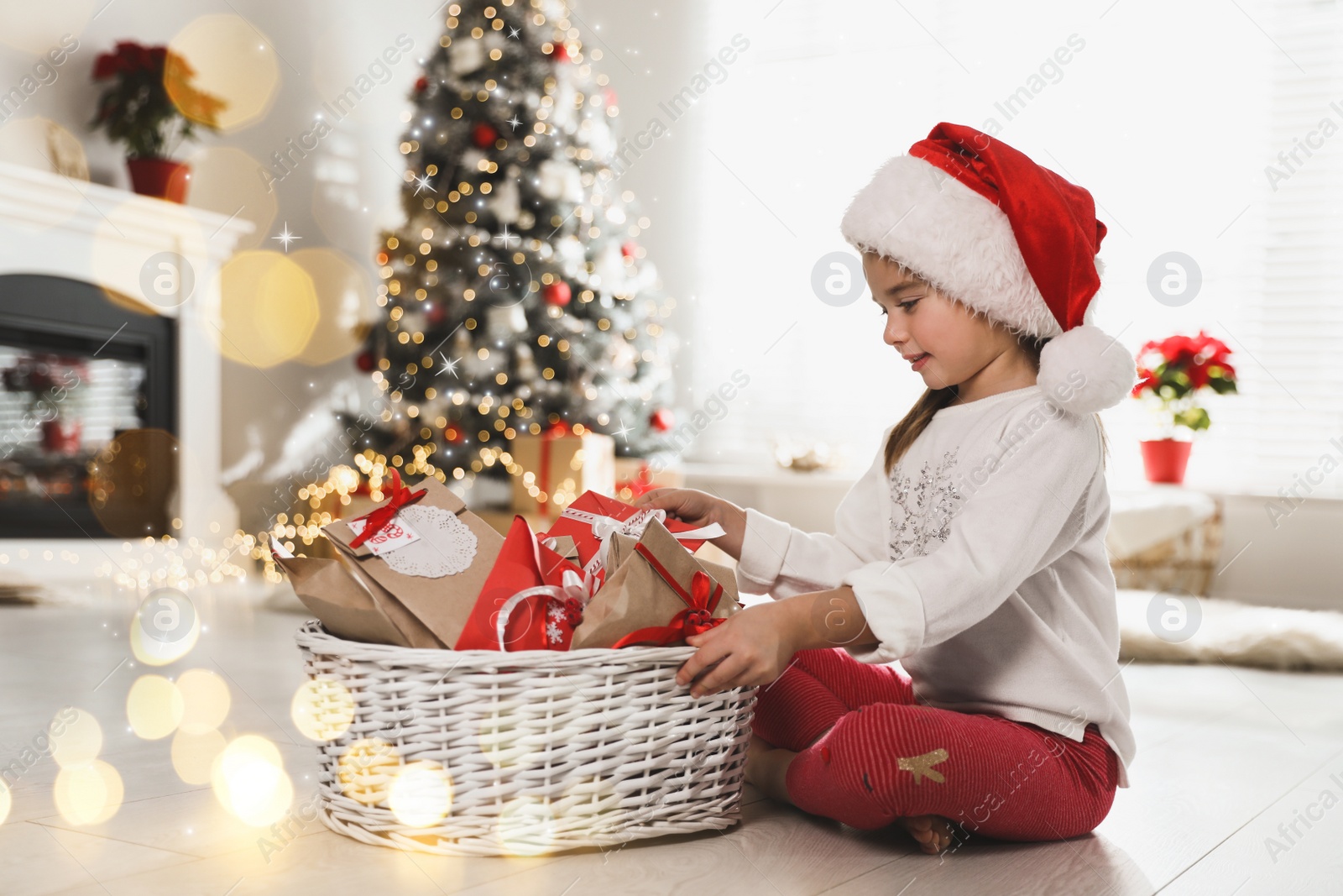 Image of Cute little girl in Santa hat taking gift from Christmas advent calendar at home. Bokeh effect