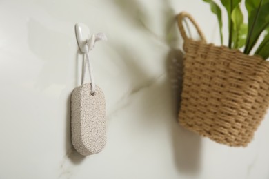 Photo of Pumice stone hanging on white wall, space for text