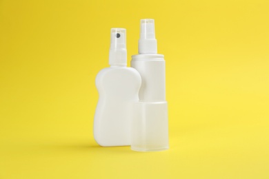 Photo of Bottles of insect repellent on yellow background