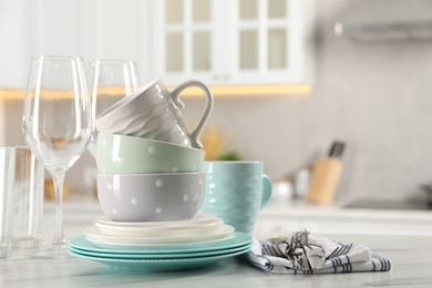 Photo of Many different clean dishware, cutlery, glasses and cups on white marble table in kitchen