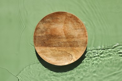 Photo of Presentation for product. Wooden podium in water on green background, top view